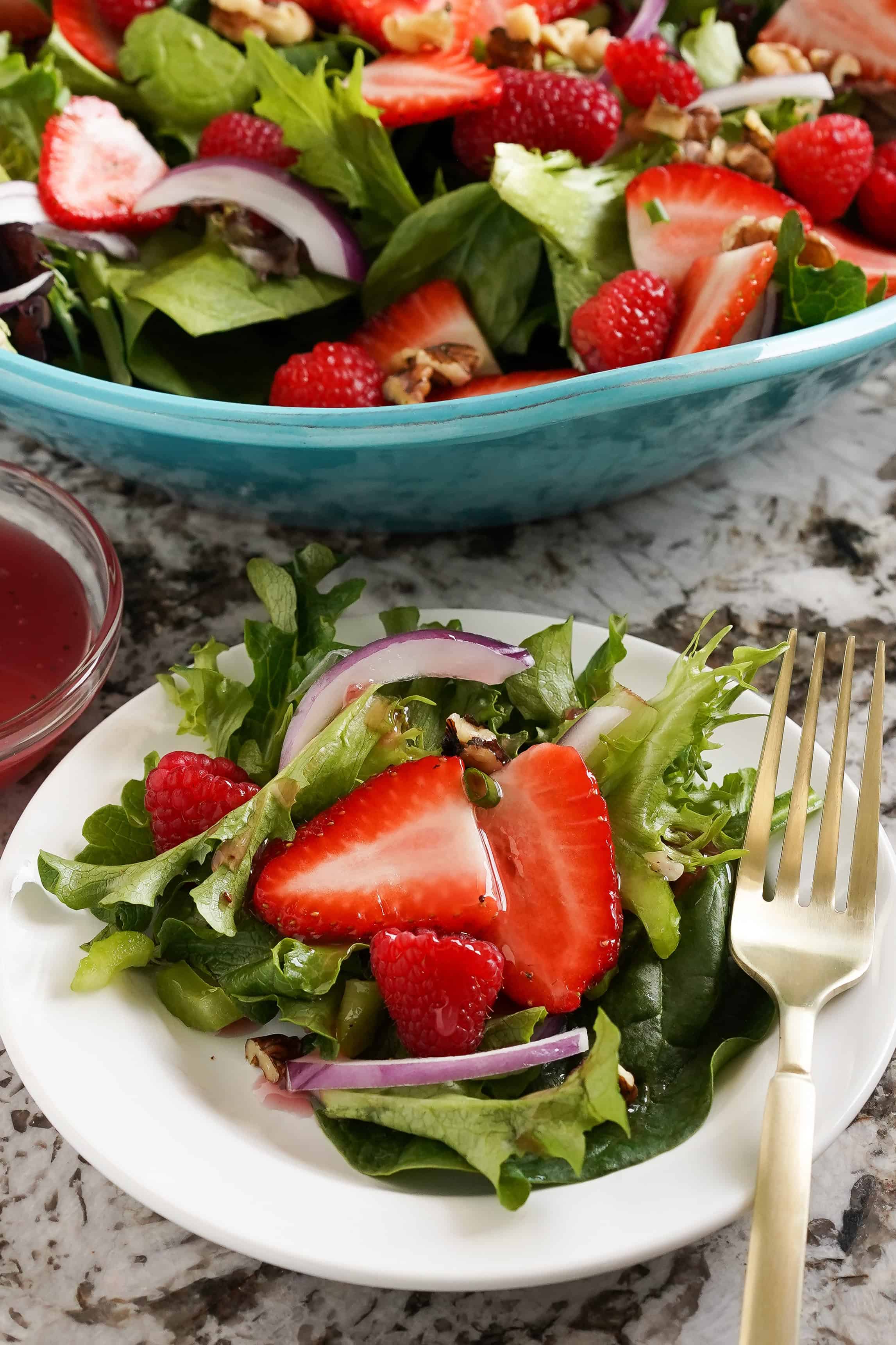 Salade avec des framboises et des fraises dans une assiette.