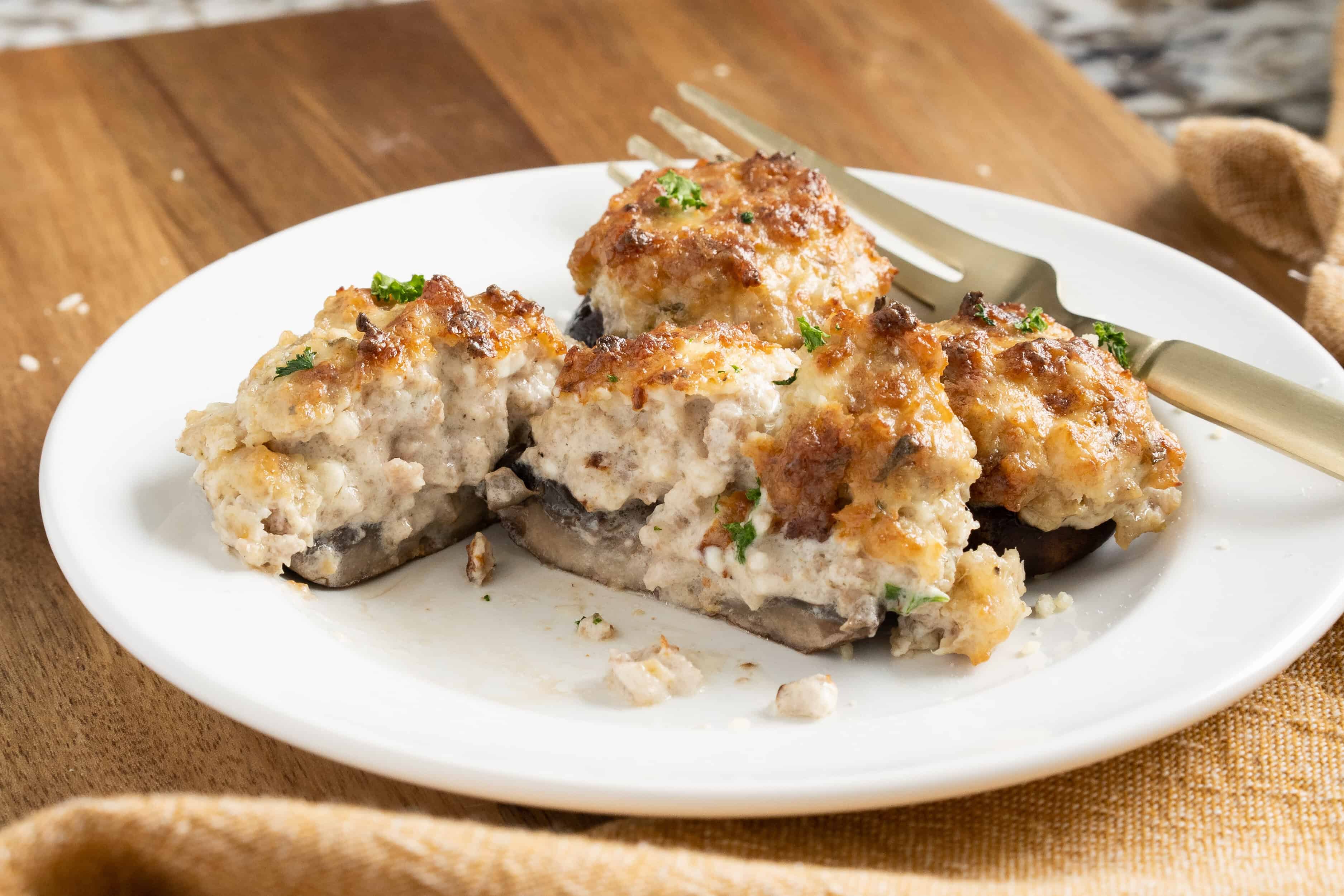 Champignon farci à la saucisse et fromage à la crème coupé sur une assiette.