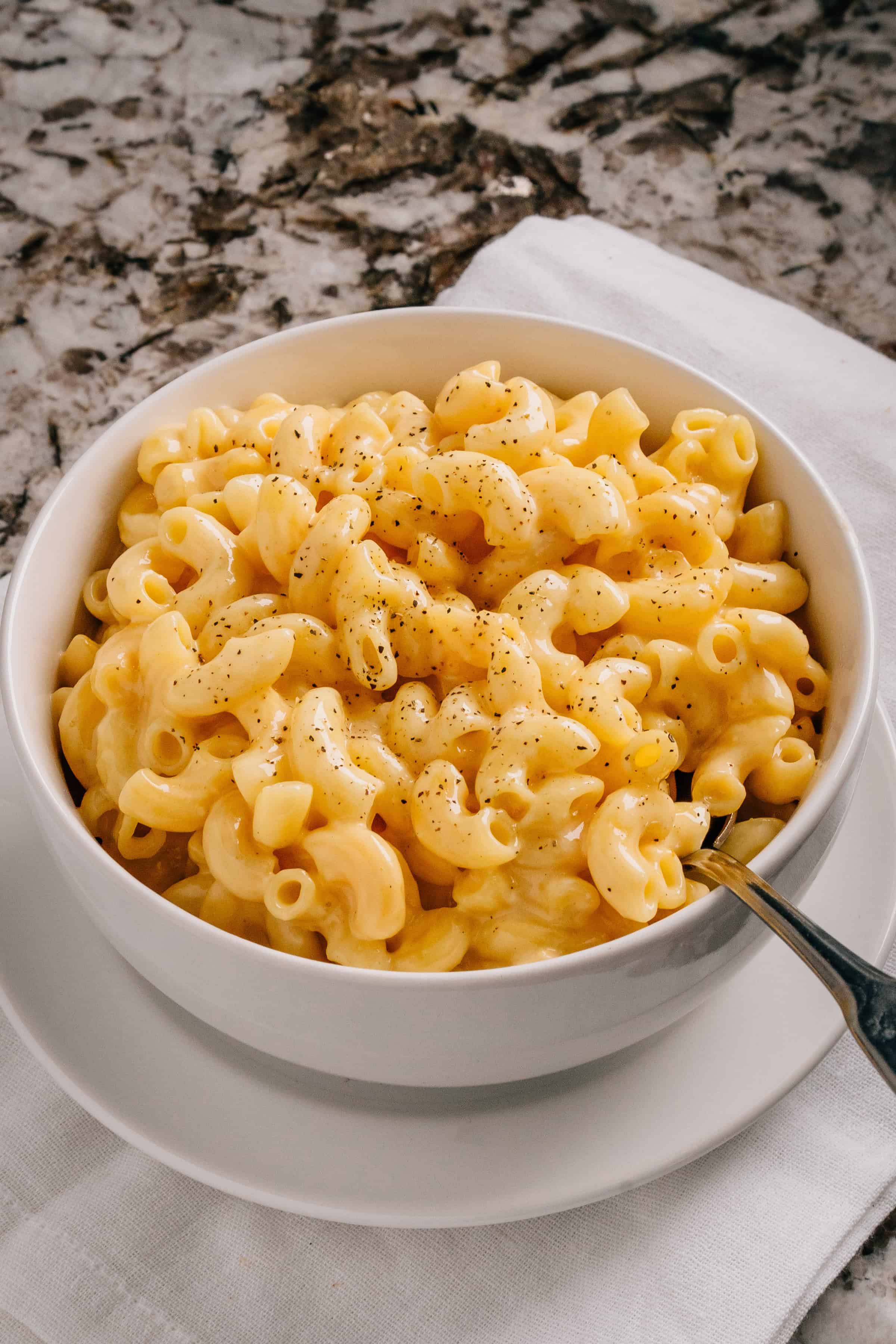 Macaroni au fromage en mijoteuse avec du poivre noir sur le dessus dans un bol.