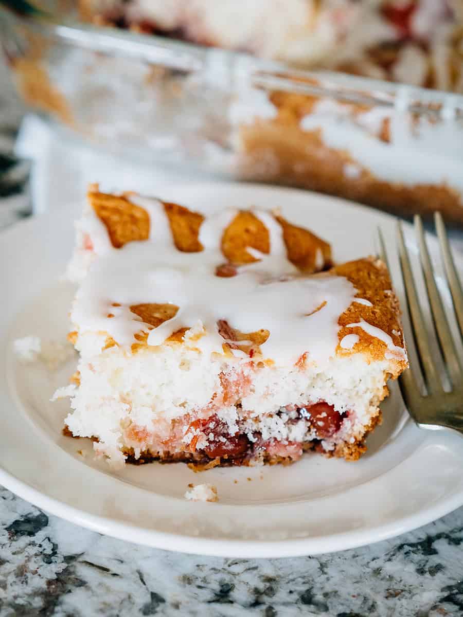 Une part de délicieux gâteau de brunch aux cerises garnie d'un simple glaçage à base de sucre glace, de lait et d'extrait de vanille.