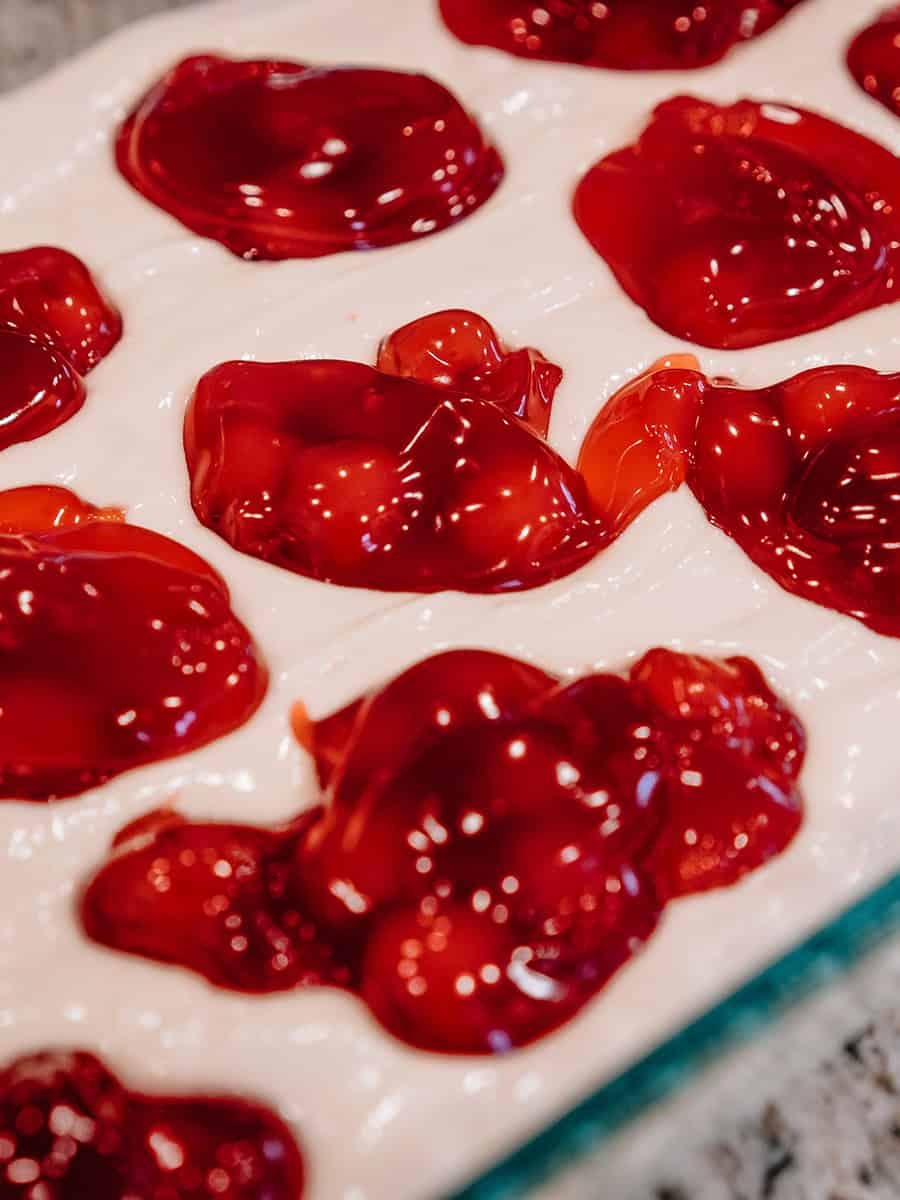 Garniture de tarte aux cerises déposée sur du mélange à gâteau blanc.