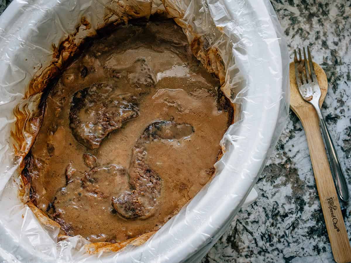 Un aperçu d'une mijoteuse avec des steaks en cube recouverts de sauce prêts à être servis.