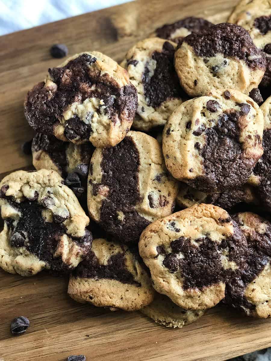 Un tas de délicieux Cookies Brookie sur une planche à découper avec des pépites de chocolat éparpillées devant.