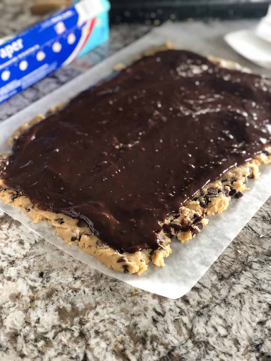 Une feuille de pâte à cookies avec de la pâte à brownie dessus. Le début du cookie brookie facile !