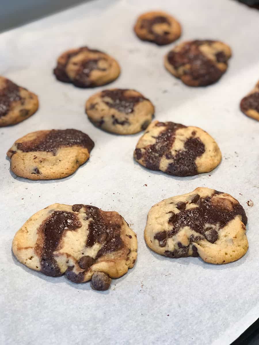 Cookies brookie fraîchement cuits sur une plaque de cuisson recouverte de papier parchemin.