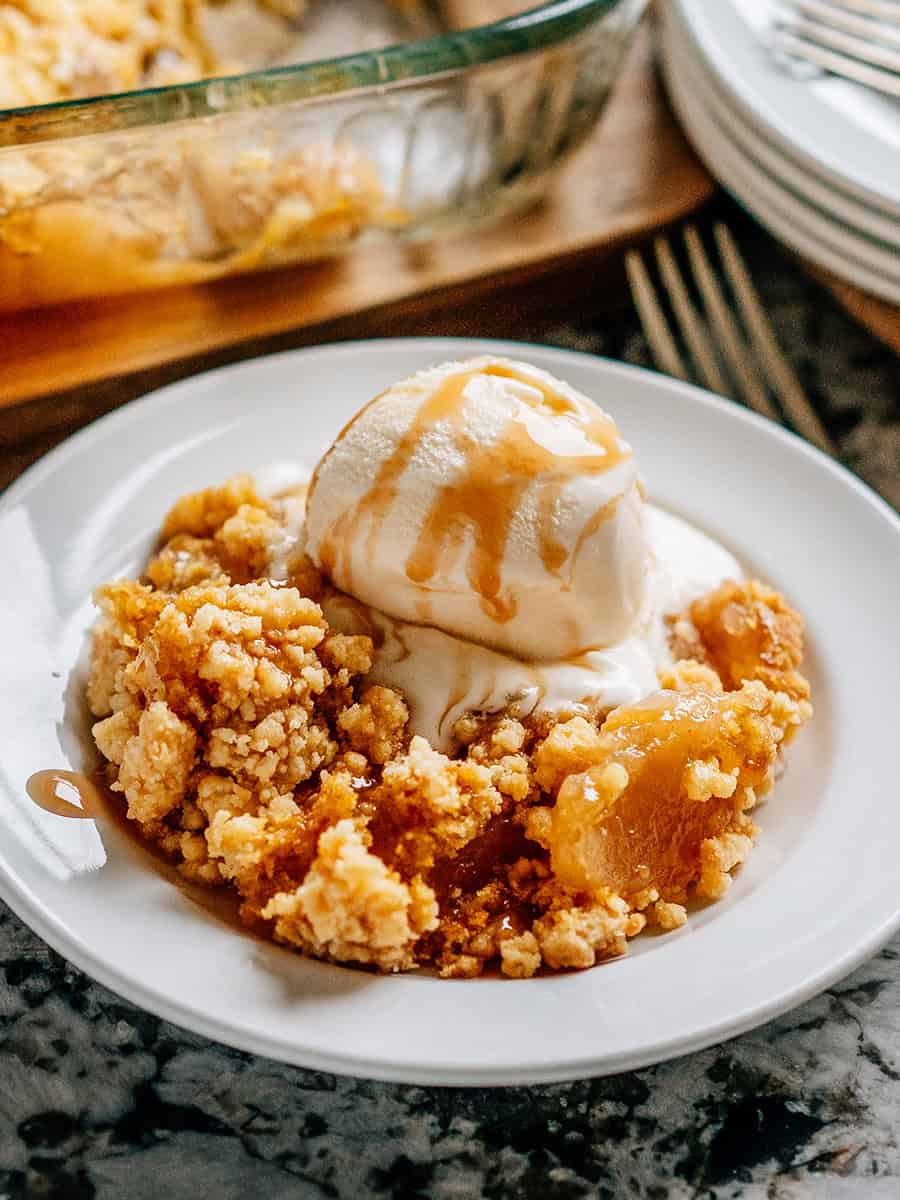 Gâteau aux pommes chaud avec une boule de glace à la vanille et du sirop de caramel drizzlé sur le dessus, prêt à être dégusté !