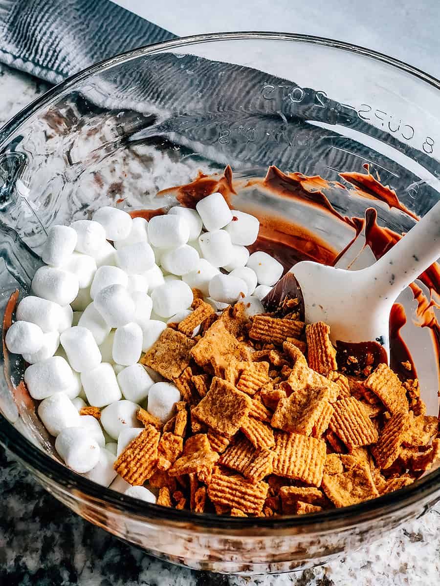 Mini guimauves et golden grahams sur le chocolat fondu prêts à être remués.