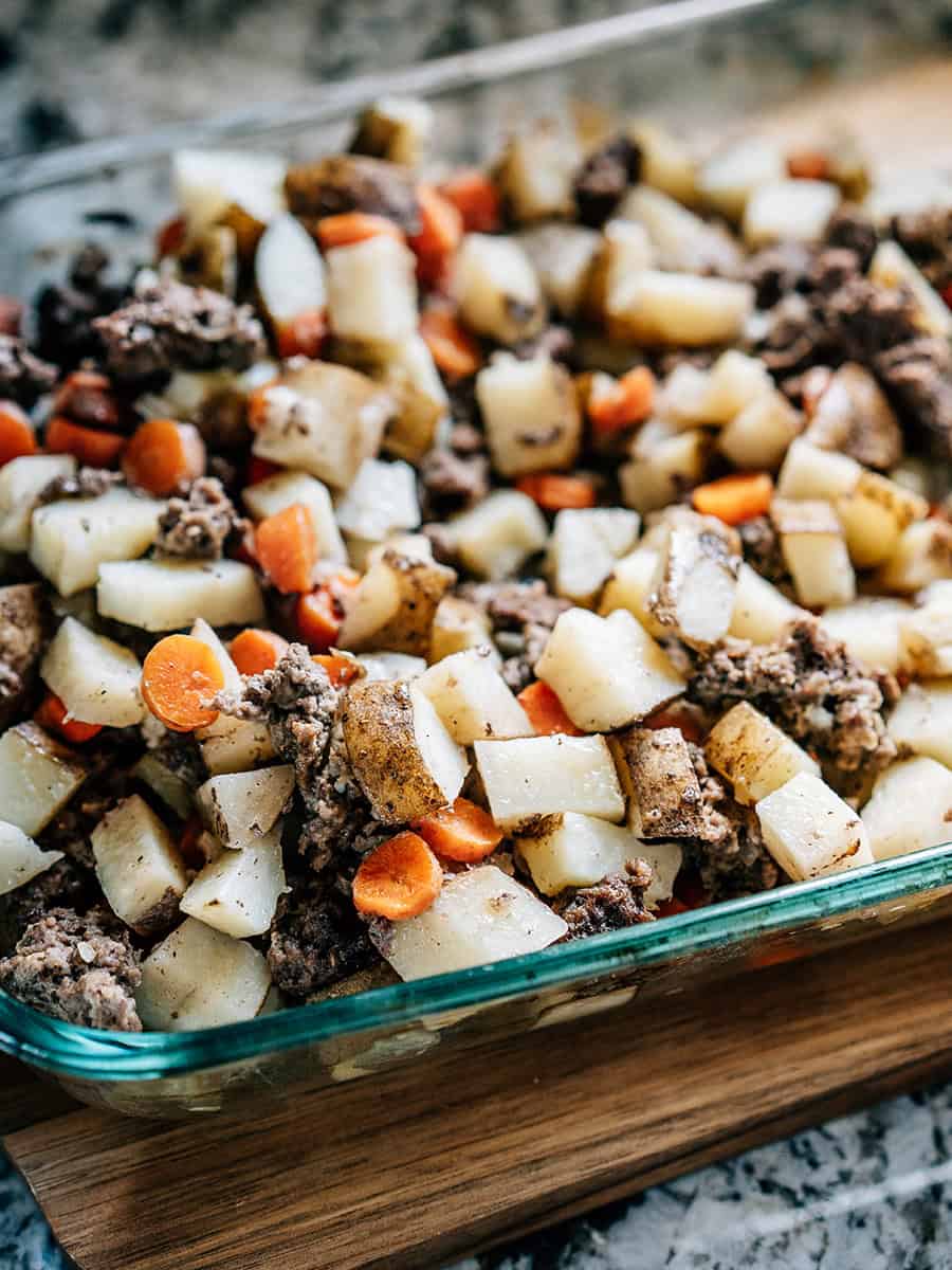 Un gratin juste cuit à la perfection : hamburger juteux, pommes de terre et carottes tendres, et oignons fanés prêts à être garnis de fromage et de crème aigre et dressés pour être dégustés !