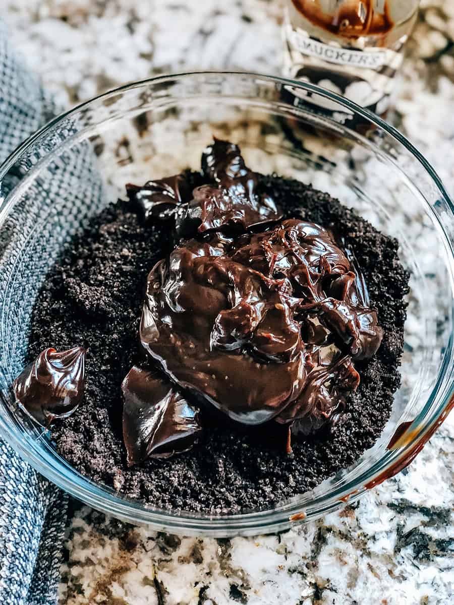 La garniture de chocolat chaud légèrement réchauffée sur le dessus des Oreos écrasés dans un bol en verre.