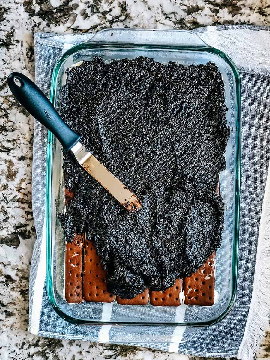 Le mélange de chocolat chaud étant étalé sur la première couche de sandwichs à la crème glacée dans le plat de cuisson.