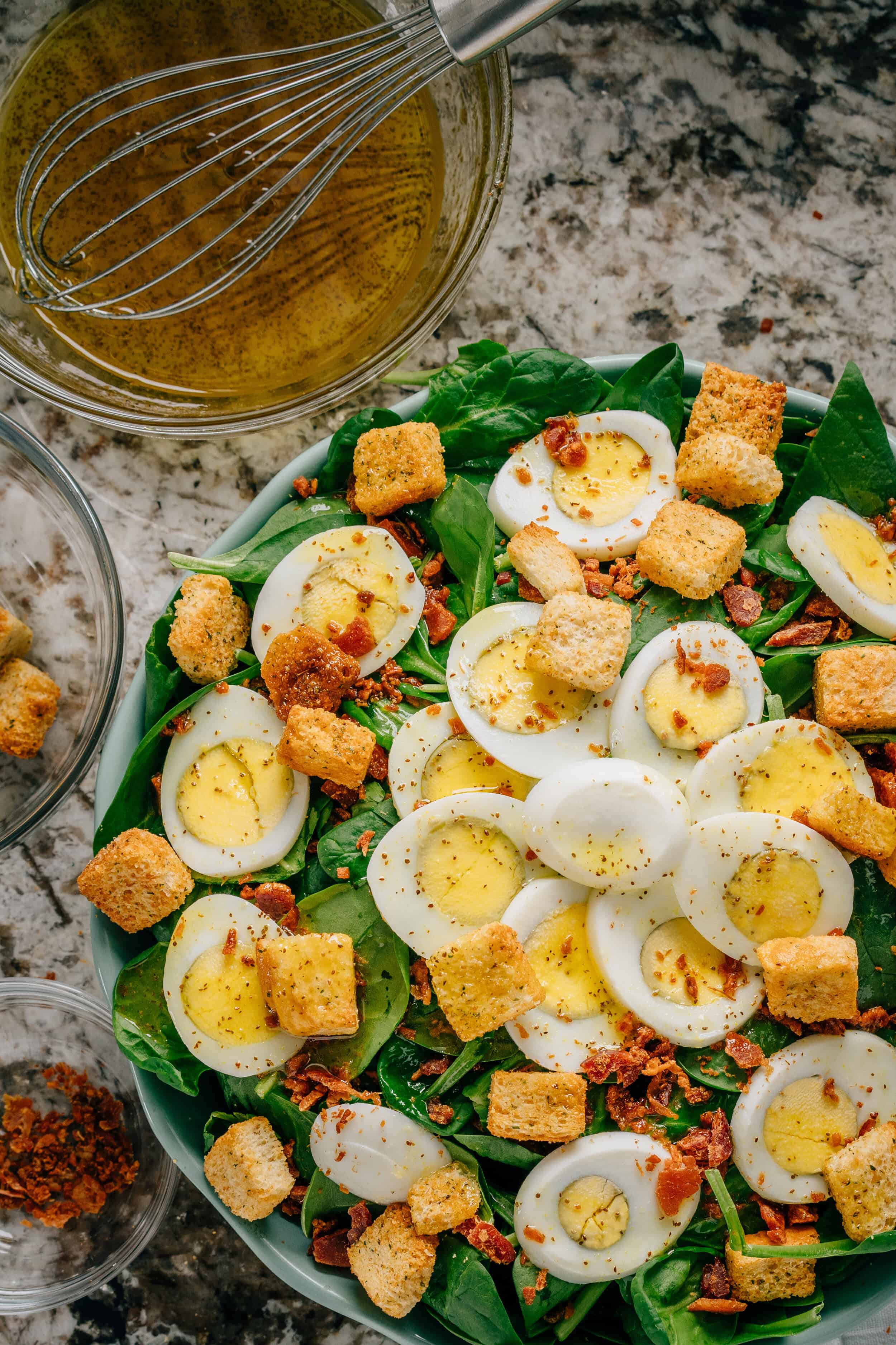 Salade d'épinards terminée. Épinards, œufs, morceaux de bacon et croûtons recouverts d'une vinaigrette maison aigre-douce.