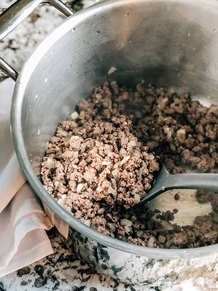 Une livre de viande hachée, d'oignons, d'ail et de sel tous dorés dans une casserole.