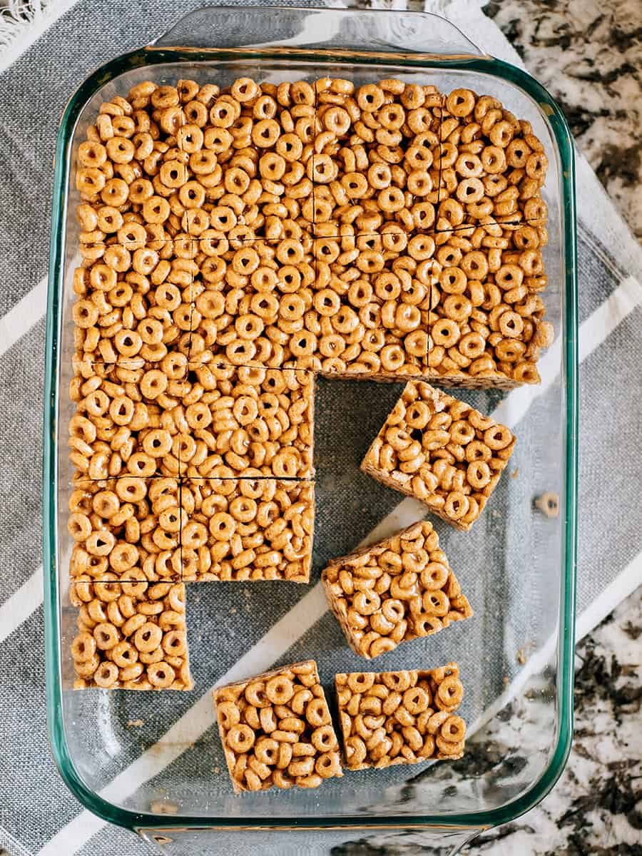 Barres de Cheerios au beurre de cacahuète dans un plat de cuisson, coupées prêtes à être servies.