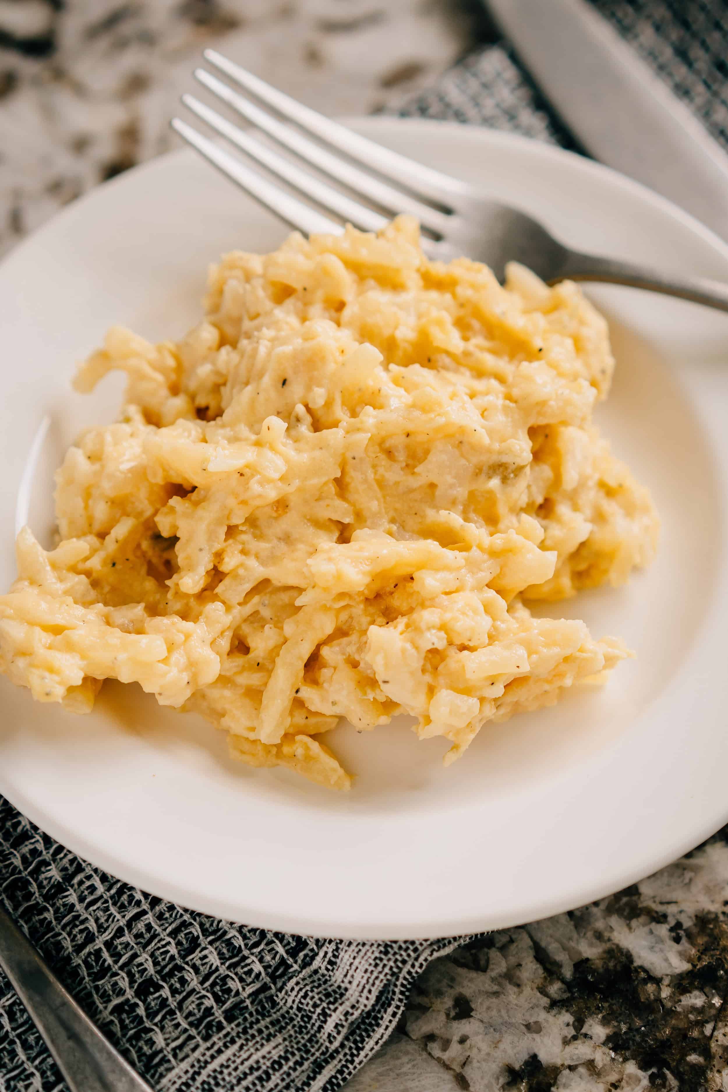 Une portion de pommes de terre crémeuses de fête préparées avec de la crème aigre, de la soupe de céleri, du fromage cheddar et des pommes de terre rissolées.