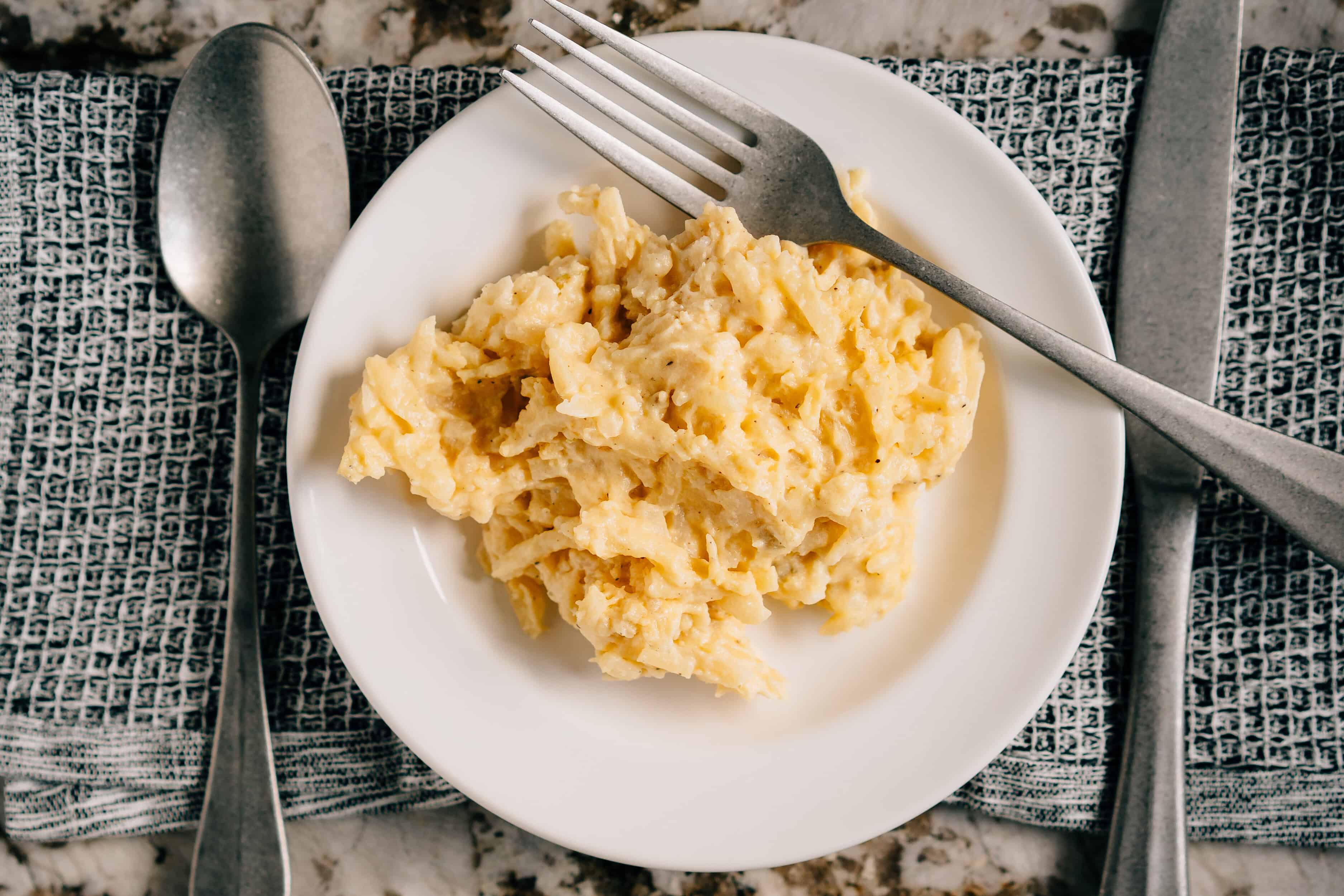 Une portion de pommes de terre crémeuses de fête préparées avec de la crème aigre, de la soupe de céleri, du fromage cheddar et des pommes de terre rissolées. Photo d'ensemble.