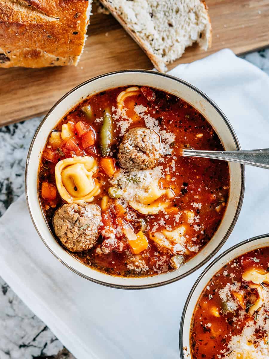 Vue d'ensemble de la soupe de boulettes de viande italiennes et de tortellini au fromage garnie de fromage parmesan.