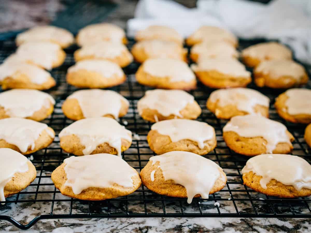 Biscuits au potiron glacés, fraîchement cuits, sur une grille de refroidissement noire.