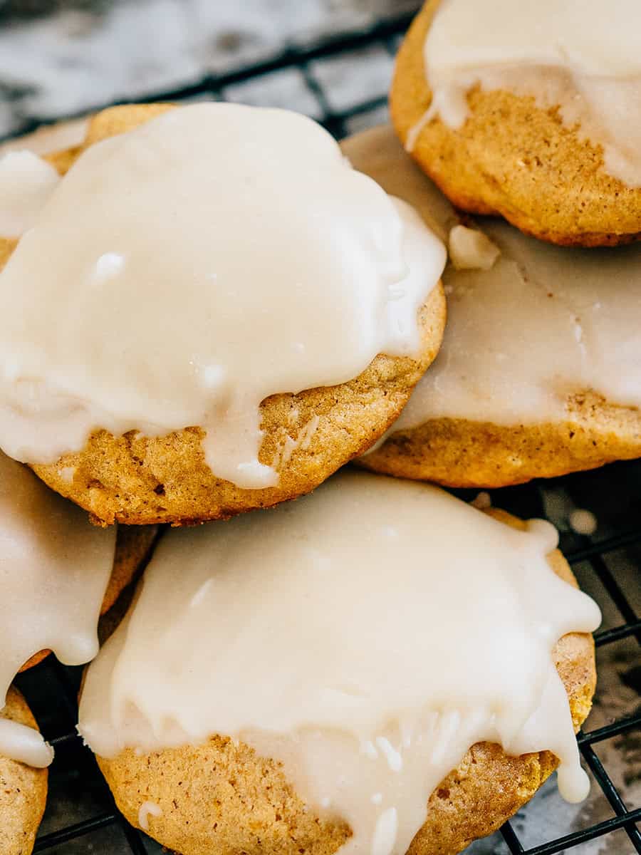 Un tas de biscuits au potiron moelleux et aérés, fraîchement cuits et surmontés d'un glaçage simple et sucré.