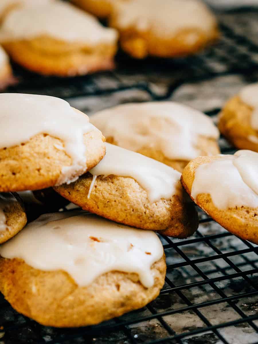 Un tas de biscuits au potiron moelleux et aérés, fraîchement cuits et surmontés d'un glaçage simple et sucré.