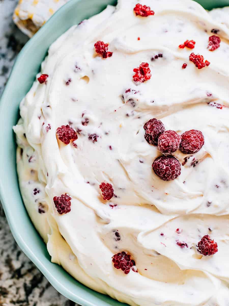 Fluff aux framboises facile préparé avec seulement quatre ingrédients prêt à être servi : yaourt à la vanille, pudding instantané à la vanille, cool whip, et framboises congelées.