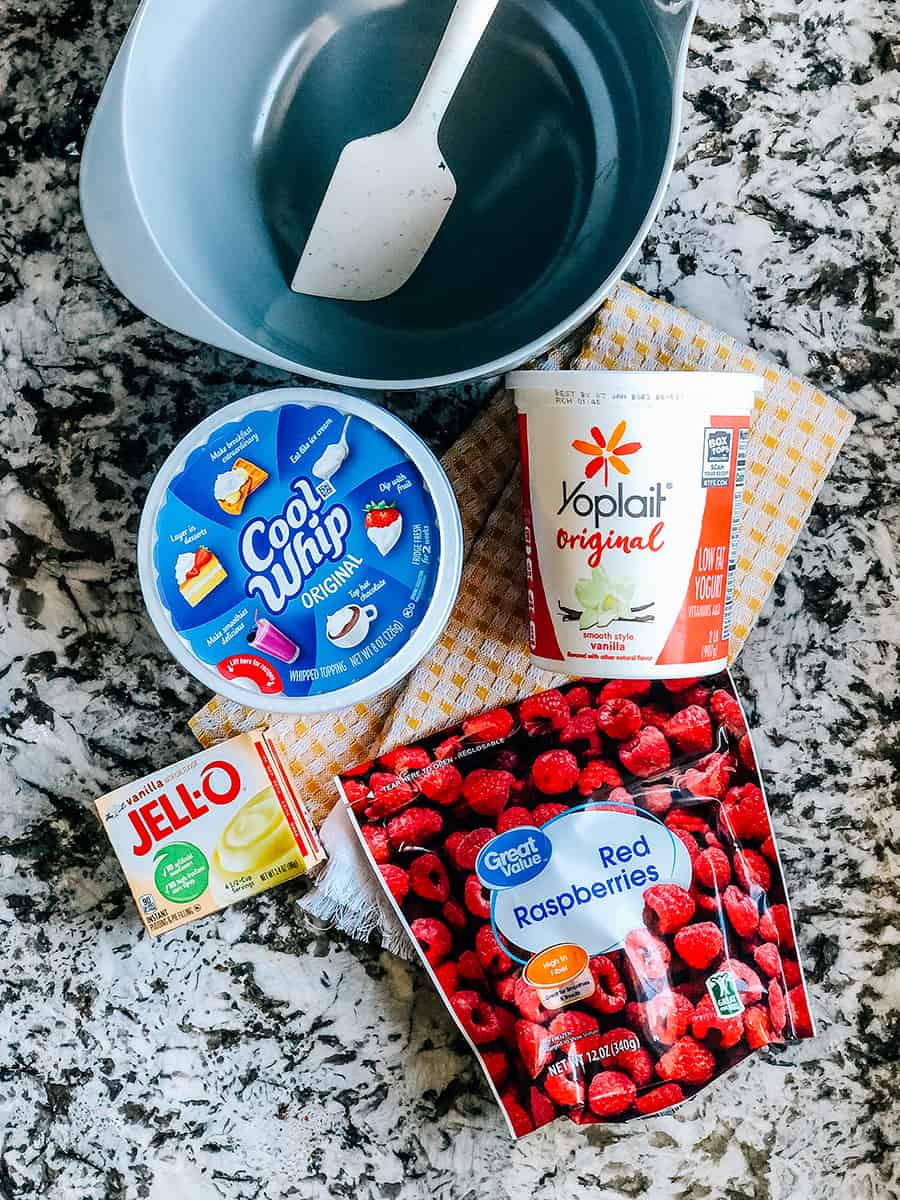 Les ingrédients du fluff aux framboises : yaourt à la vanille, sachet de pudding instantané à la vanille, cool whip et framboises congelées.