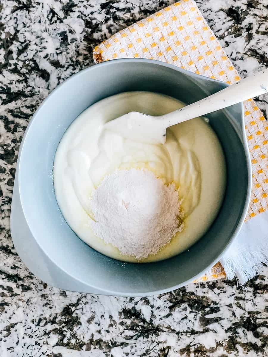 Photo du processus de fluff aux framboises : Le sachet de pudding instantané versé sur le yaourt à la vanille.