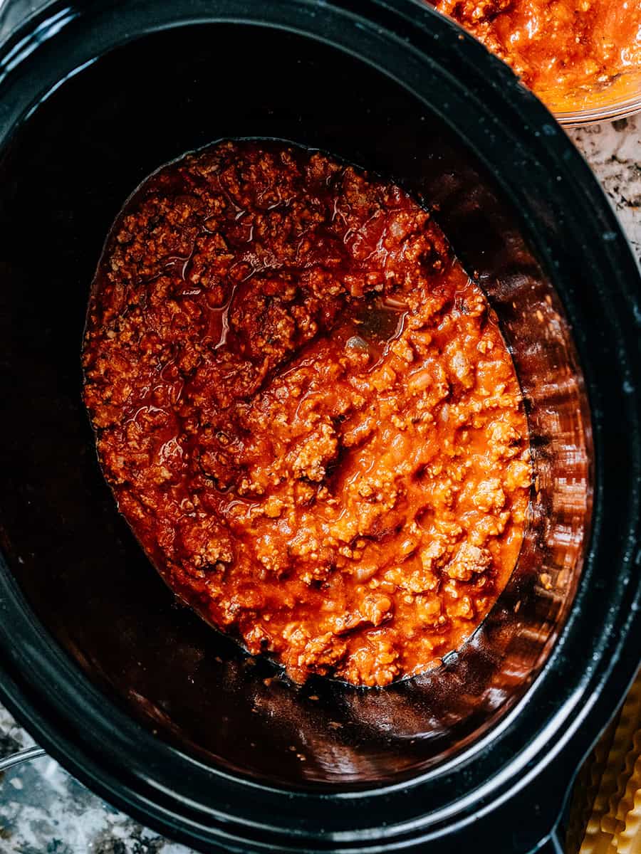 Sauce à viande couvrant le fond d'une mijoteuse. La première étape dans la superposition de la lasagne à la mijoteuse.