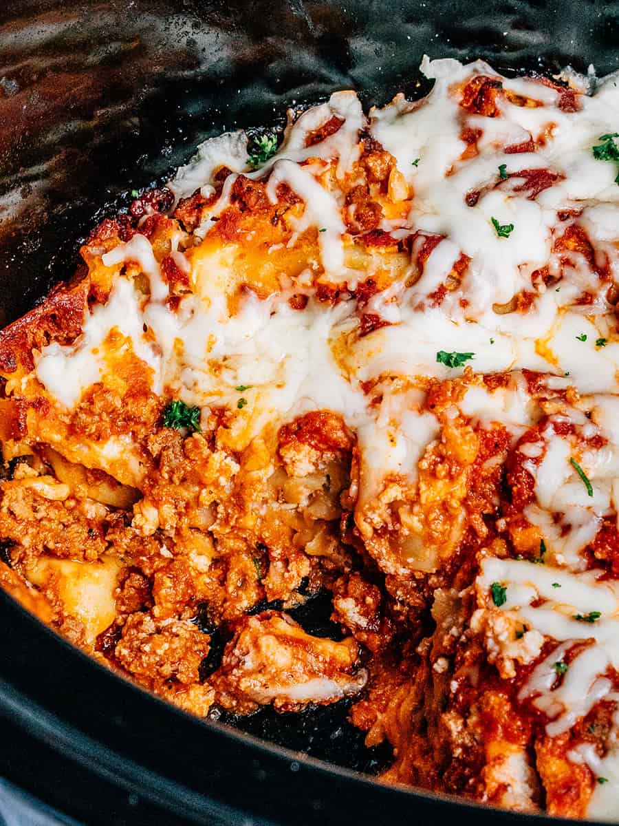 Gros plan de lasagne chaude et délicieuse dans une mijoteuse montrant les couches de nouilles, fromage et sauce à viande.