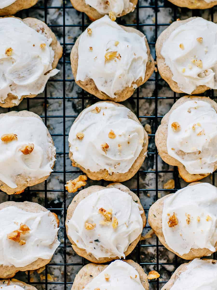 Cookies de courgettes glacés, délicieux et faciles, avec des noix hachées et un glaçage au fromage à la crème reposant sur une grille.