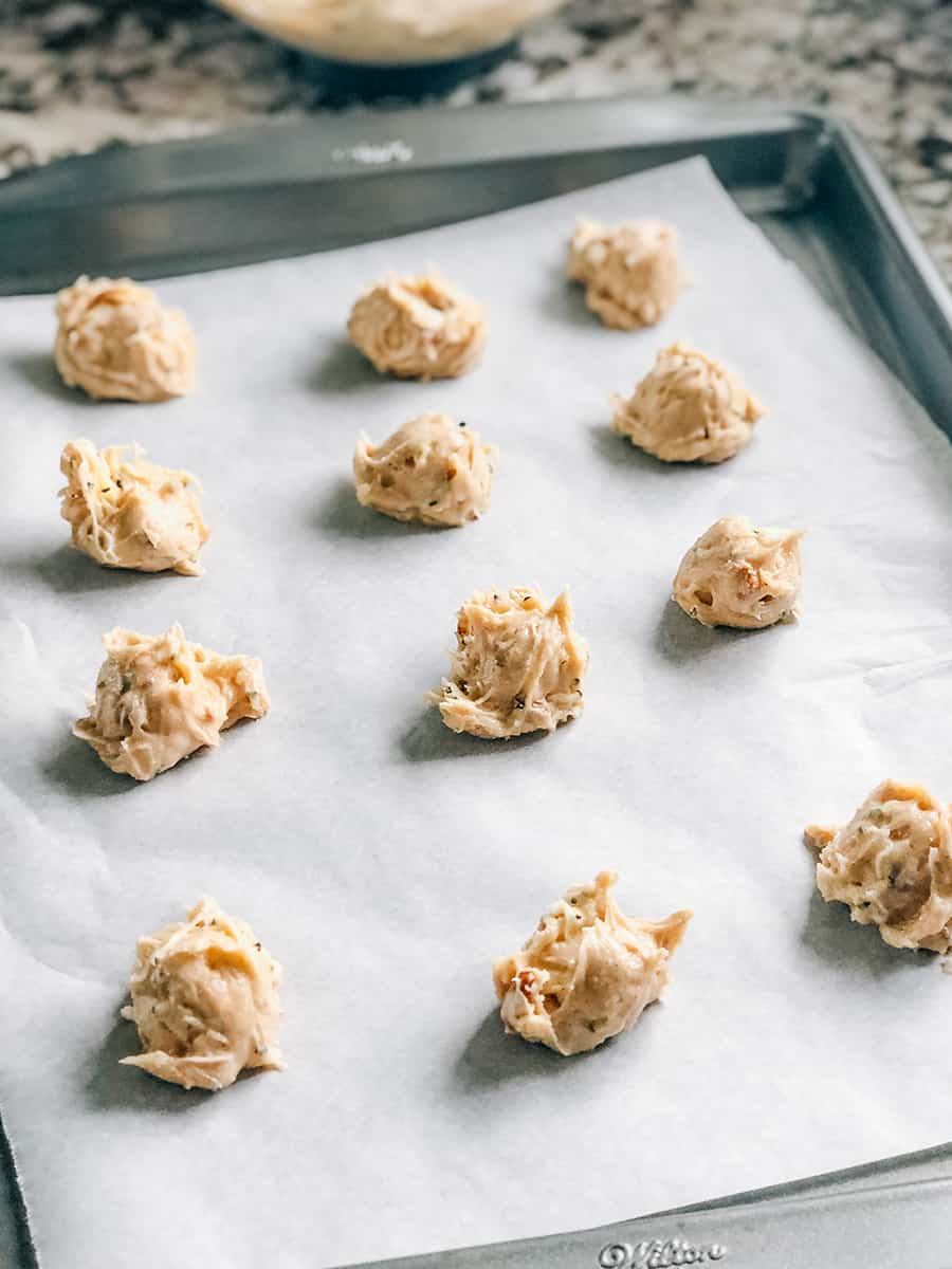 Des boules de pâte à biscuits portionnées sur une plaque à biscuits prêtes à être cuites en délicieux cookies de courgettes.