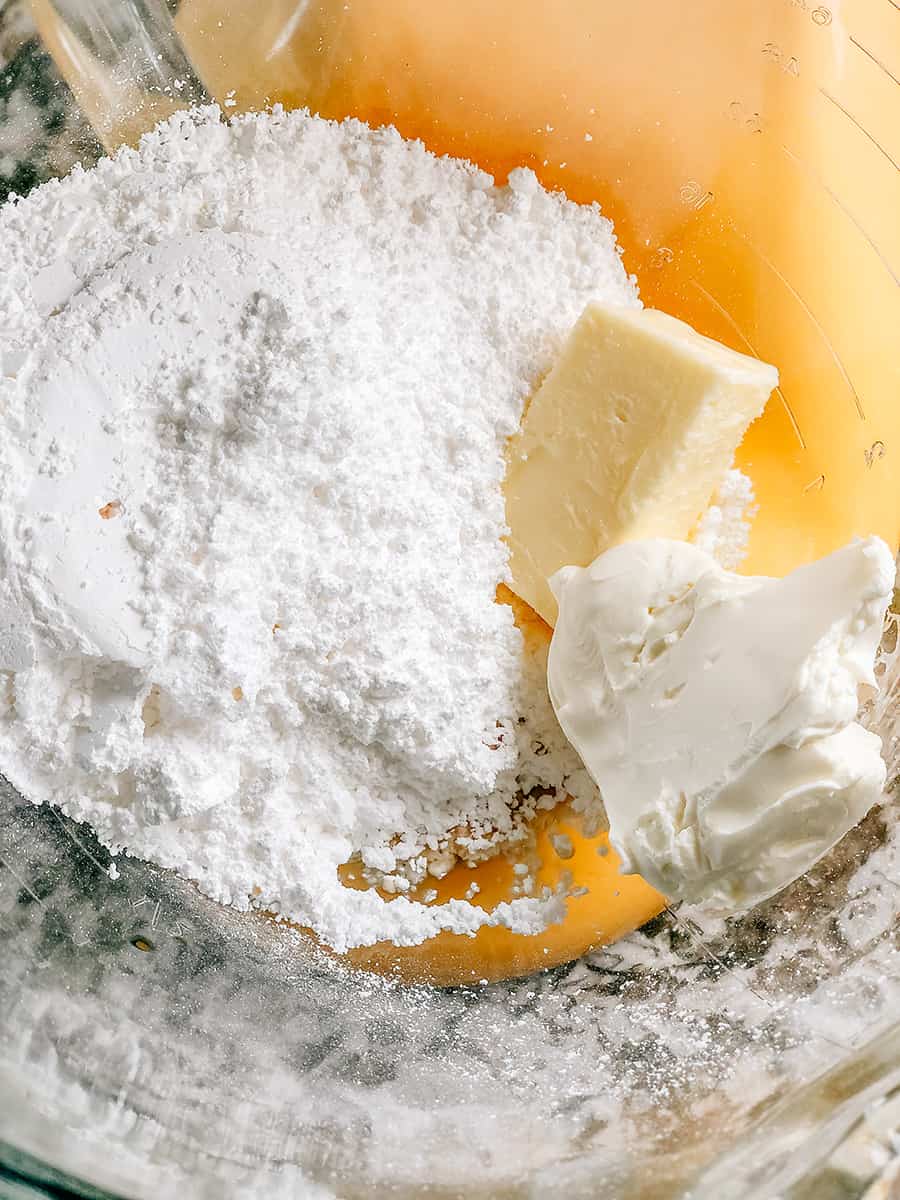 Les ingrédients du glaçage au fromage à la crème dans un bol à mélanger, prêts à être crémeux ensemble.