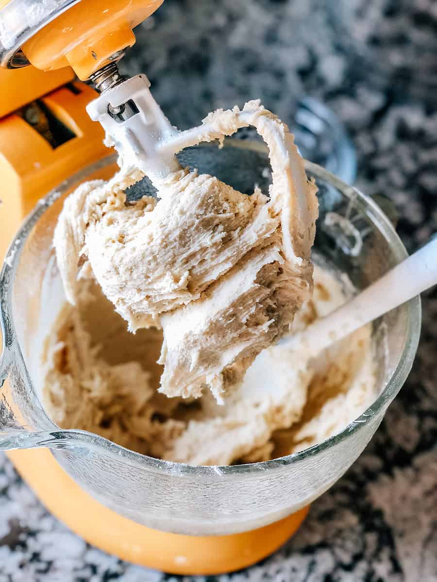 Le batteur d'un robot pâtissier couvert de beurre, sucre et œufs crémeux. La première étape pour préparer la pâte à biscuits sucrés.
