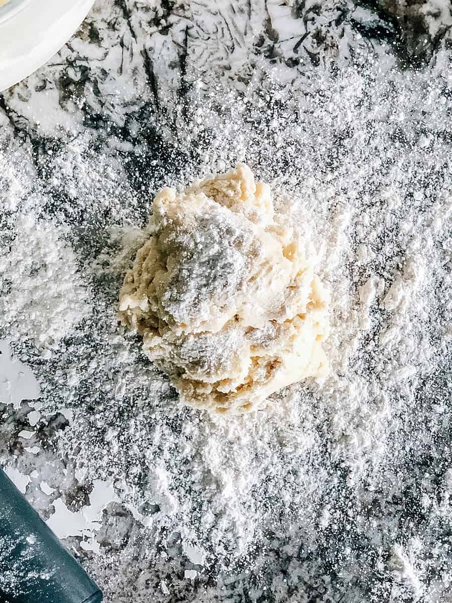Une boule de pâte à biscuit sucré refroidie saupoudrée de farine prête à être étalée.