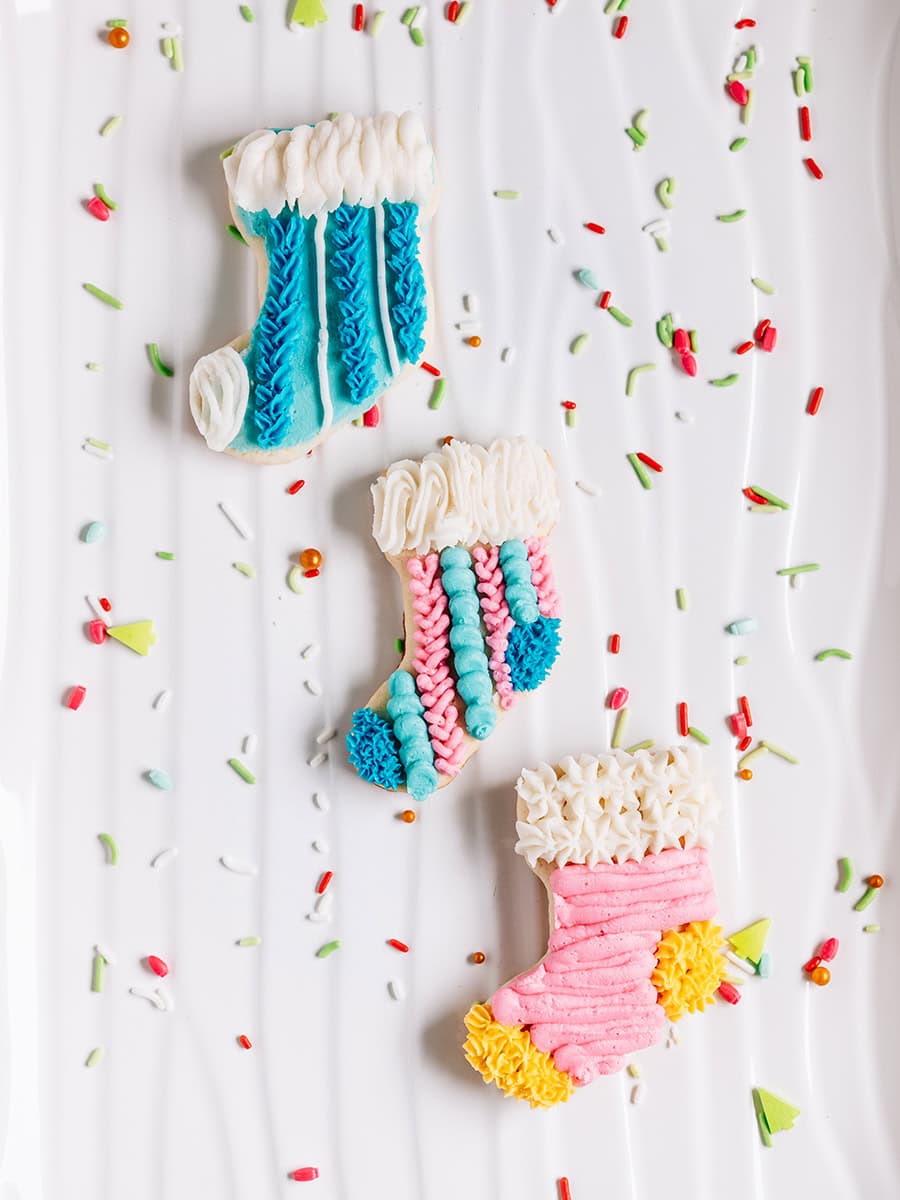 Trois biscuits en forme de chaussette de Noël sur un plateau.