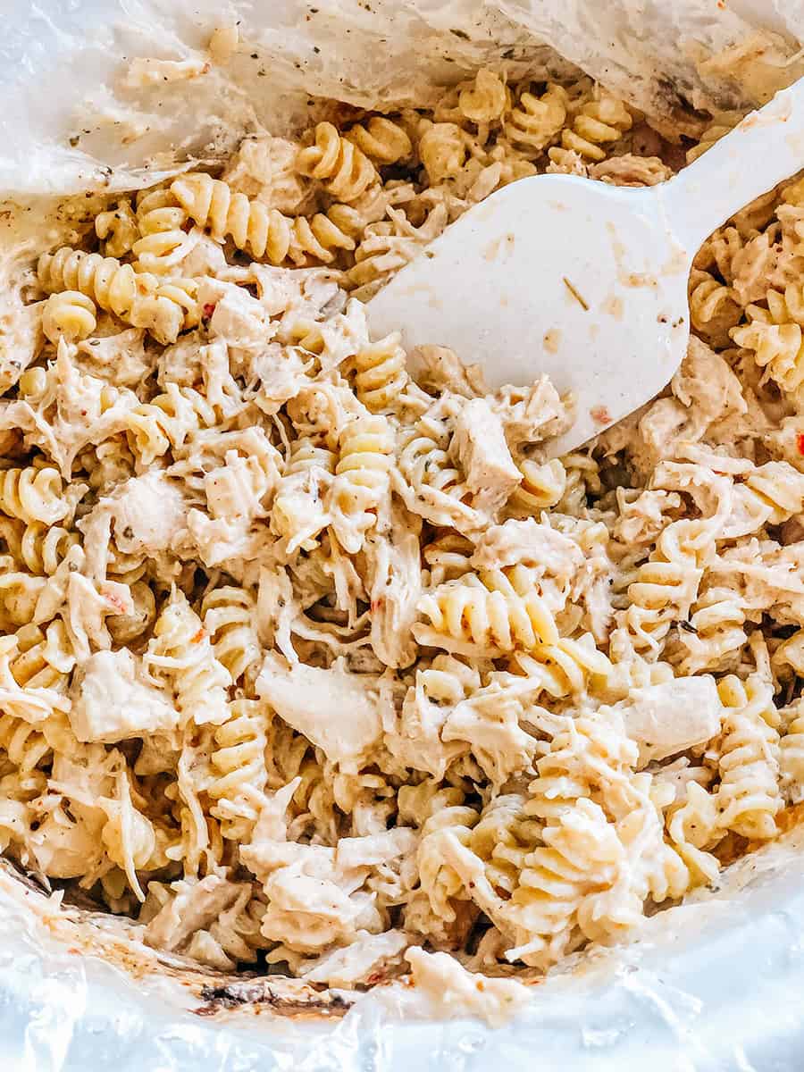 Les pâtes rotini ajoutées et ensuite mélangées au poulet déchiqueté à l'ail et au parmesan.