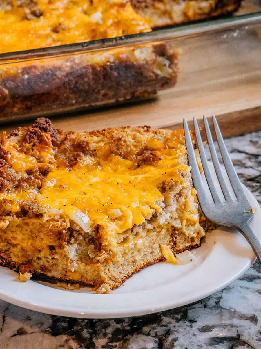 Une tranche de casserole de petit-déjeuner entièrement cuite sur une assiette. Une croûte extérieure bien dorée et un centre fromager qui fond dans la bouche. Miam !