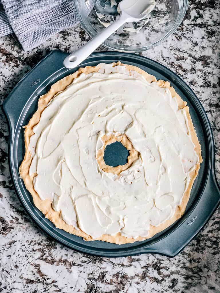 Une photo du mélange de fromage à la crème étalé sur les rouleaux croissants pincés.