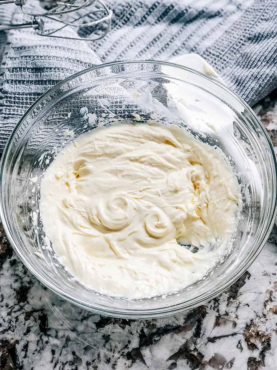 Mélange crémeux de fromage à la crème, sucre en poudre, œuf et vanille dans un bol.