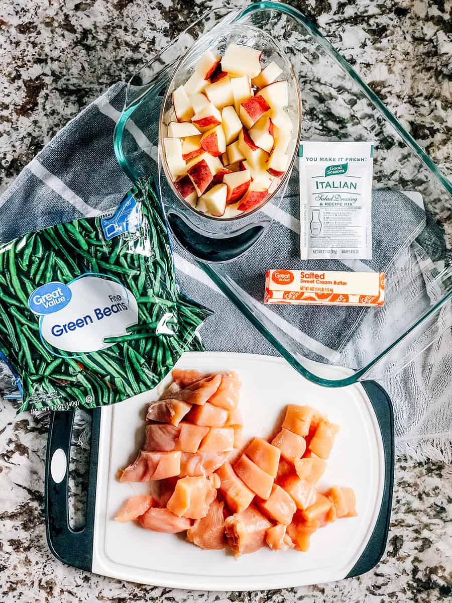 Les ingrédients pour ce plat de poulet italien, haricots verts et pommes de terre : poitrine de poulet en dés et pommes de terre rouges, un sac de haricots verts congelés, 1 bâton de beurre et un sachet d'assaisonnement de vinaigrette italienne avec un plat de cuisson de 9x13 pouces.