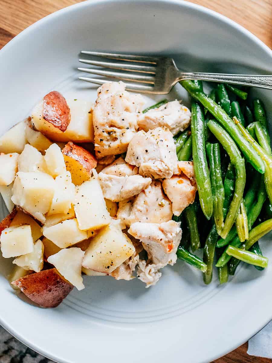 Poulet italien cuit avec des haricots verts et des pommes de terre rouges, servi et prêt à manger.