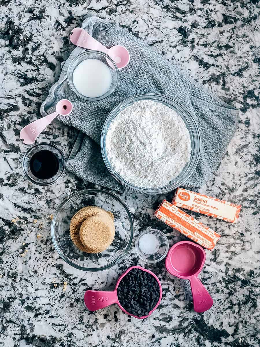 Vue d'ensemble des ingrédients de la pâte à cookies comestible : farine, sucre brun clair, beurre, vanille, sel et lait.