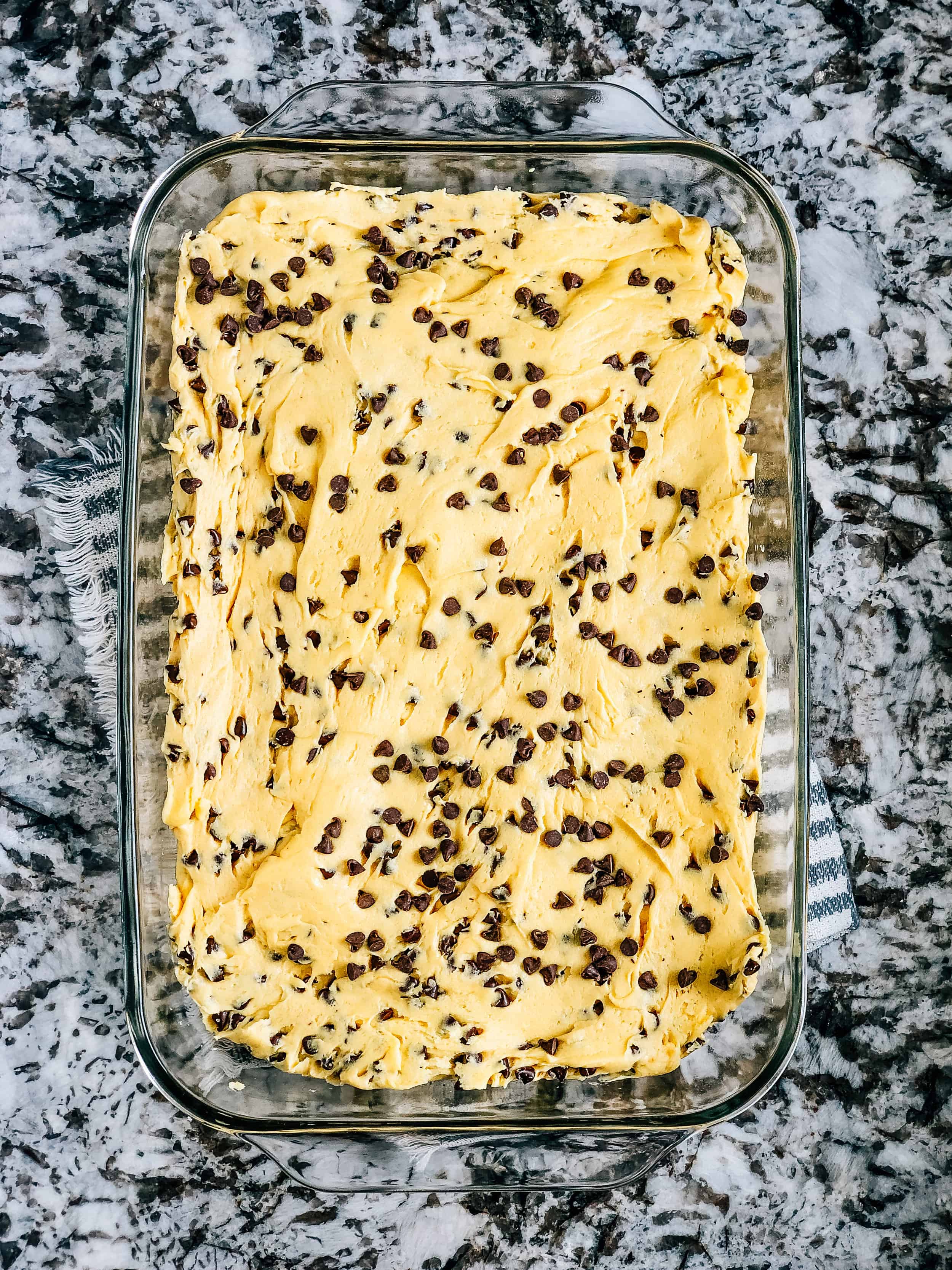 La pâte de barre de cookie chocolaté paresseuse étalée dans un plat de cuisson en verre de 23x33 cm.