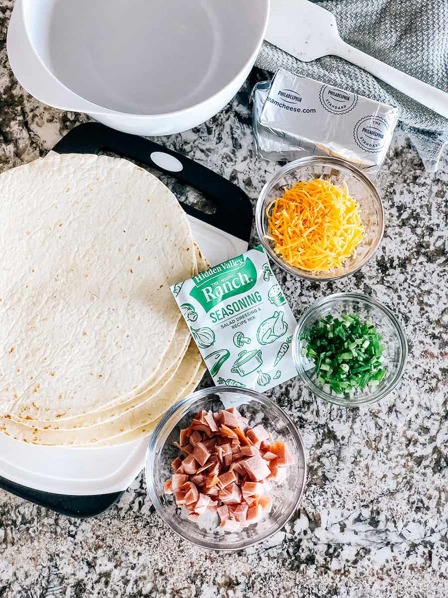 Ingrédients pour les tortillas de jambon et fromage ranch : 5 grandes tortillas de farine, jambon haché, oignons verts hachés, fromage cheddar râpé, fromage à la crème et un sachet d'assaisonnement ranch.