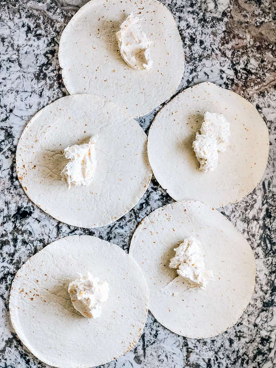 Le mélange de fromage à la crème divisé en 5 sur les tortillas extra grandes.