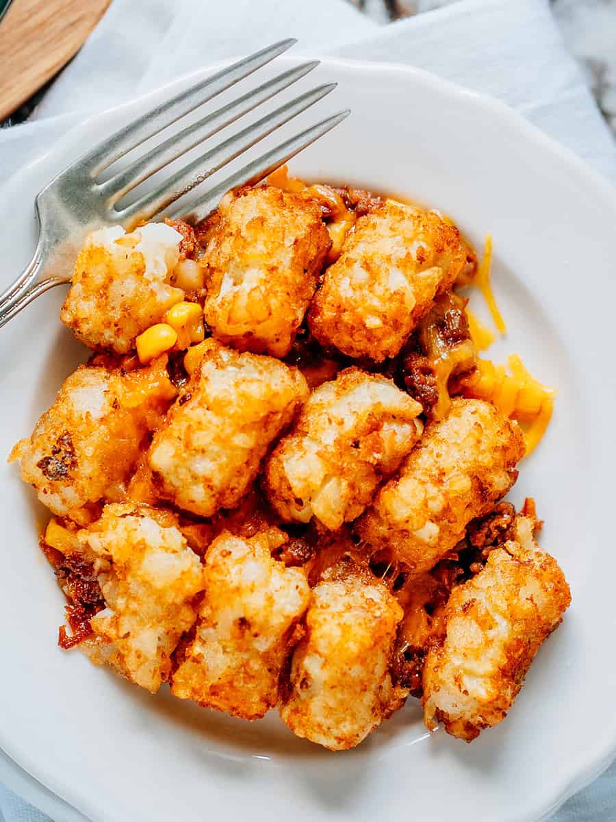 Aperçu d'une assiette de casserole de Tater Tot faite avec des Sloppy Joes, du fromage râpé et du maïs.