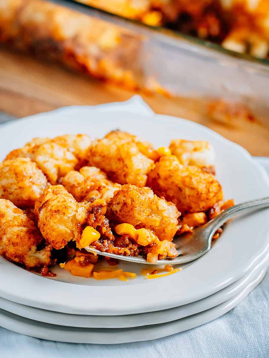 Une fourchette pleine de casserole de Tater Tot aux Sloppy Joes sur une assiette montrant le Sloppy Joe sucré, le fromage fondu et les Tater Tots croustillants.