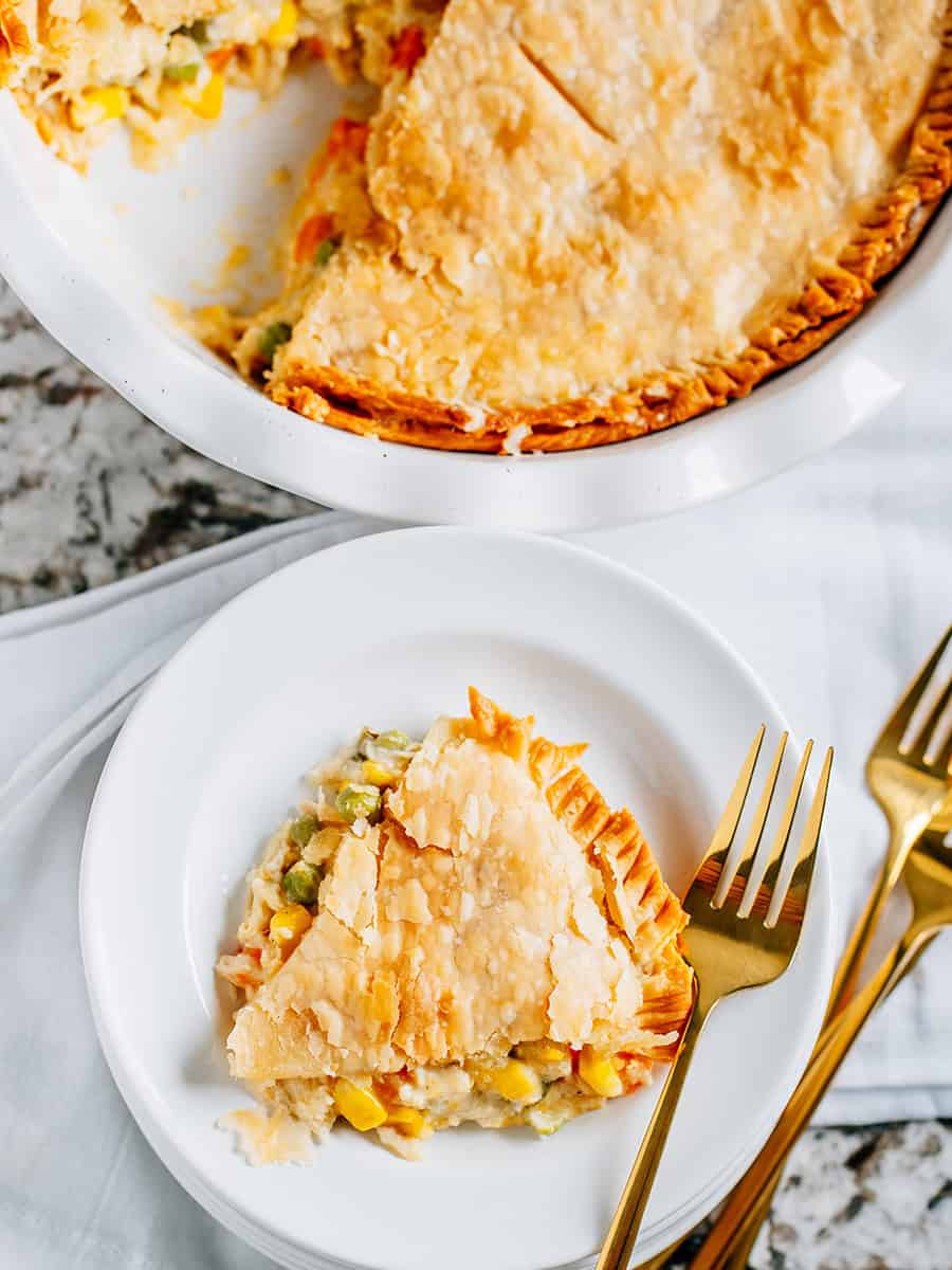 A slice of chicken pot pie with the pie in the background.