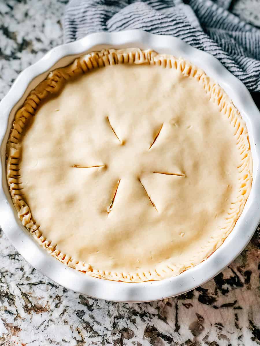 The top pie shell fitted on top of the filling and sealed with a forked edge with slits cut into the top.