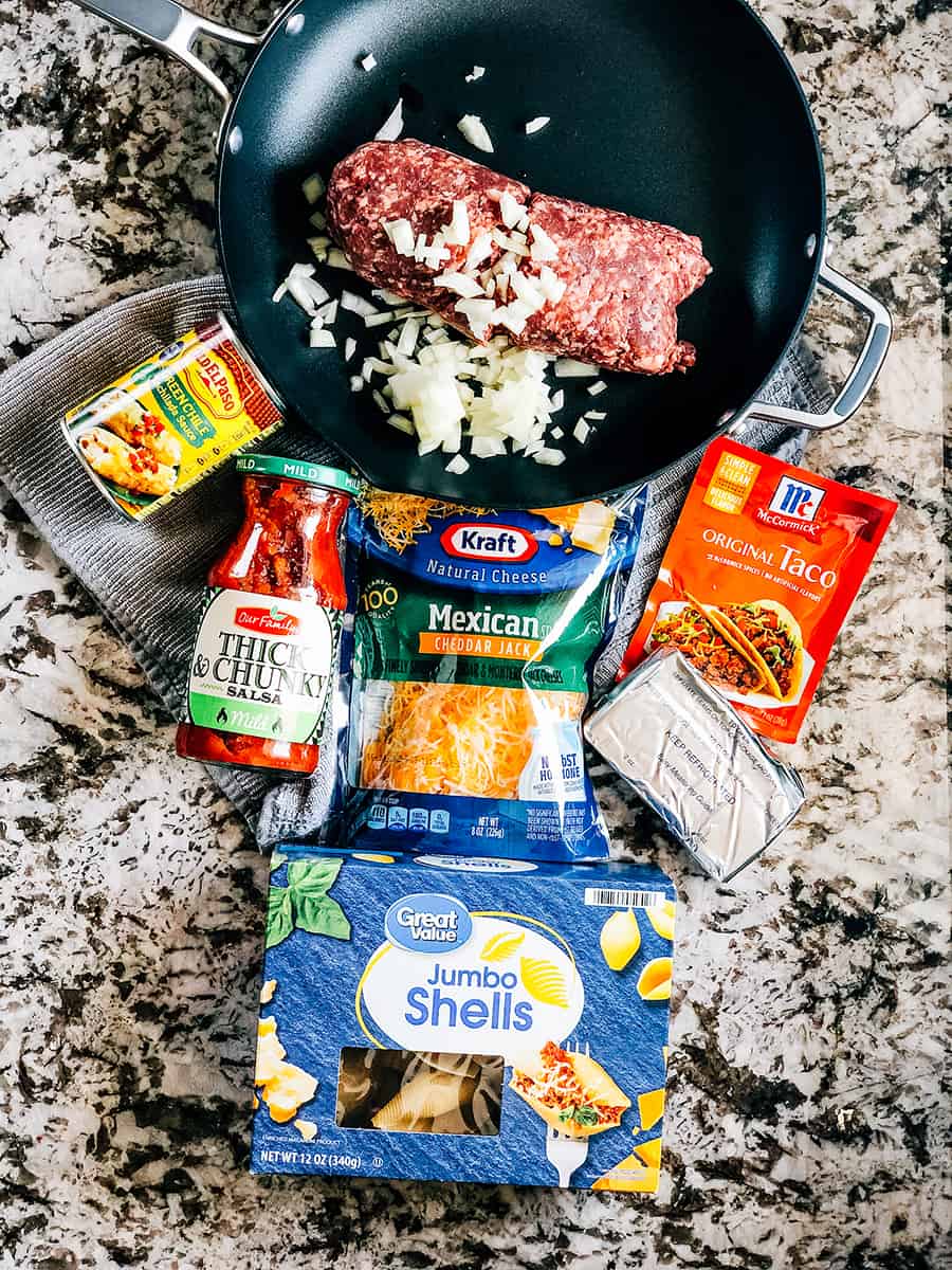 Ingrédients pour les coquilles farcies mexicaines : grosses coquilles de pâtes, viande hachée, oignon haché, mélange de fromage râpé mexicain, assaisonnement à taco, fromage à tartiner, salsa et sauce enchilada.