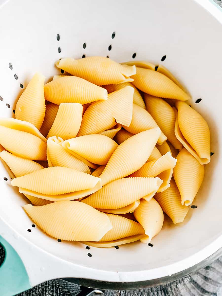 Coquilles de pâtes cuites, égouttées et refroidies dans une passoire.